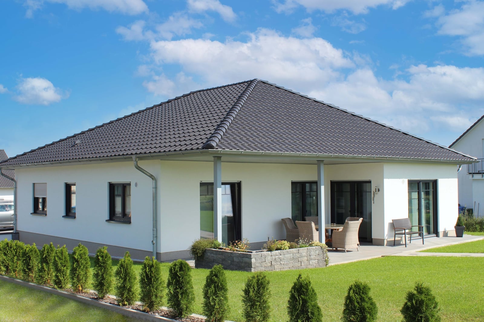 Fertiggestellter Bungalow mit anthrazitfarbenem Walmdach, Terrasse und angelegtem Garten