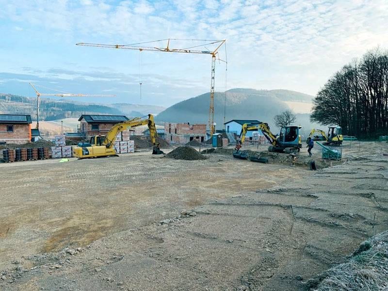 Zwei Bagger auf einem vorbereiteten Baufeld neben Baumaterial