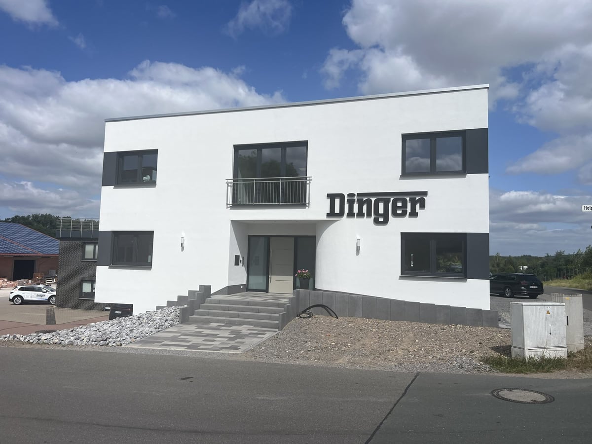 Firmensitz von Dinger Bauunternehmen: weißes Bürogebäude mit dem Dinger-Schriftzug an der Fassade