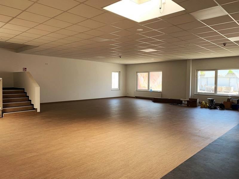 Fertiggestellter großer Innenraum mit neu verlegtem Holzboden, abgehängter Rasterdecke und Treppe – Umbau in Marsberg