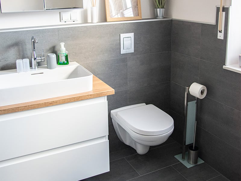 Badezimmer mit großformatig gefliester Wand, Waschtisch auf Holzkonsole und Wand-WC