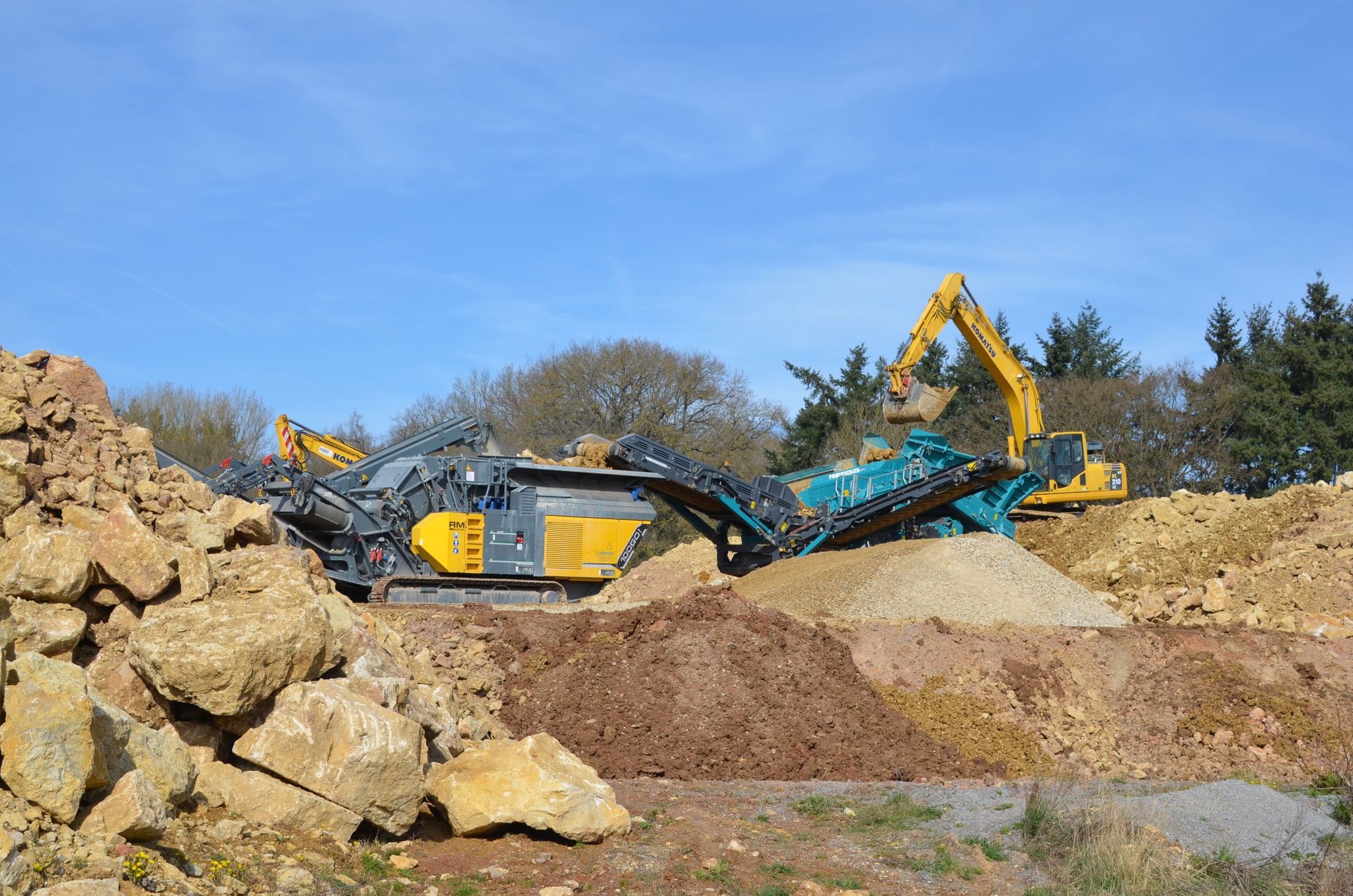 Siebanlage und Bagger auf dem Recyclinghof von Dinger Bauunternehmen, davor Halden aus Sand, Boden und Gestein