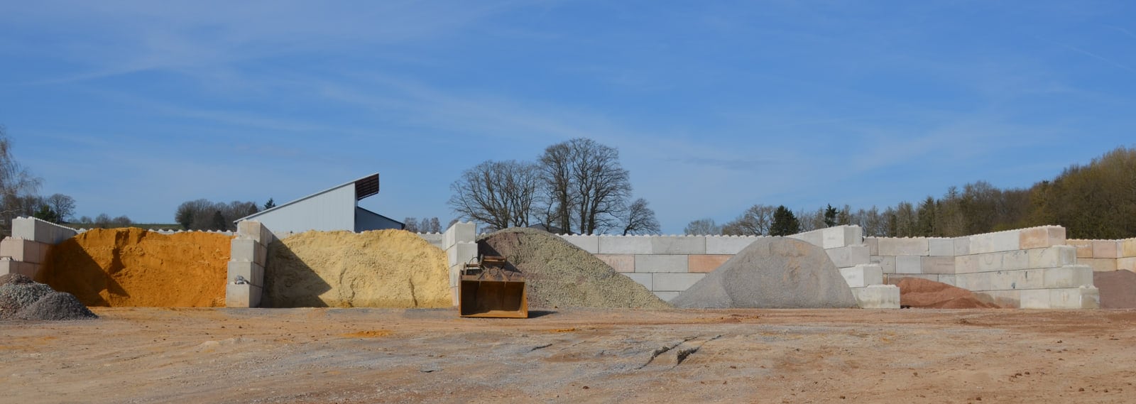 Materialboxen auf dem Lagerplatz, gefüllt mit Sand, Kies und Splitt in verschiedenen Körnungen