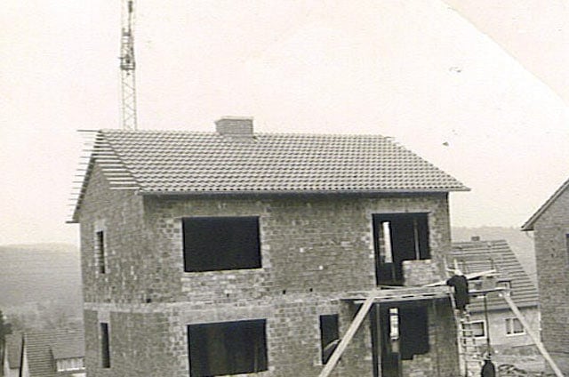 Schwarzweißaufnahme eines Wohnhaus-Rohbaus mit Gerüst aus Holzstangen