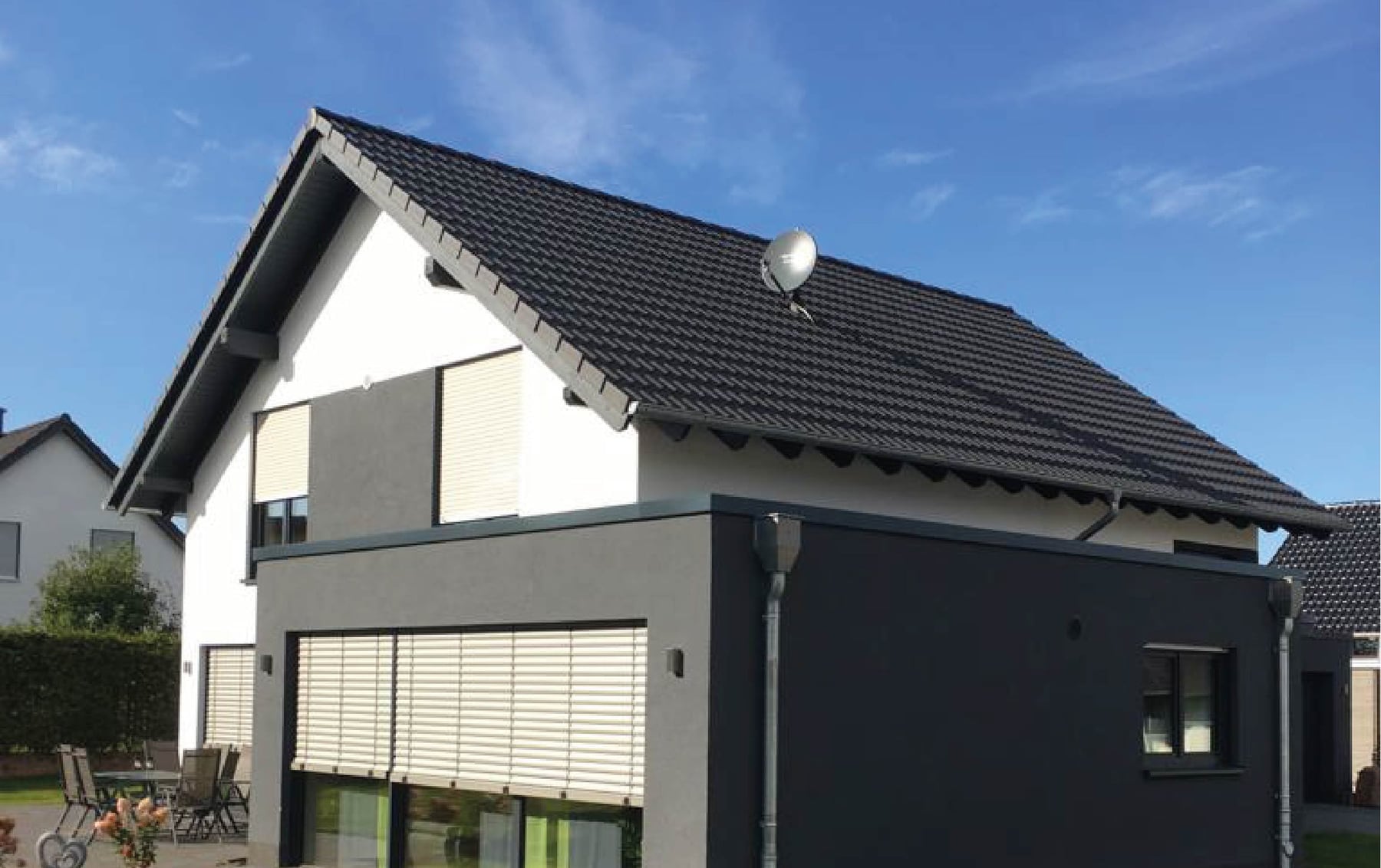 Einfamilienhaus mit dunkler Ziegeleindeckung, First, Ortgang und angebautem Flachdachteil