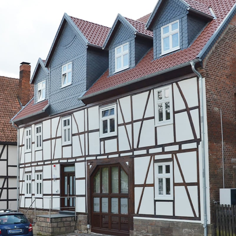 Dasselbe Fachwerkhaus nach der Sanierung: drei Schiefergauben, schieferverkleidete Flächen und instand gesetztes Fachwerk
